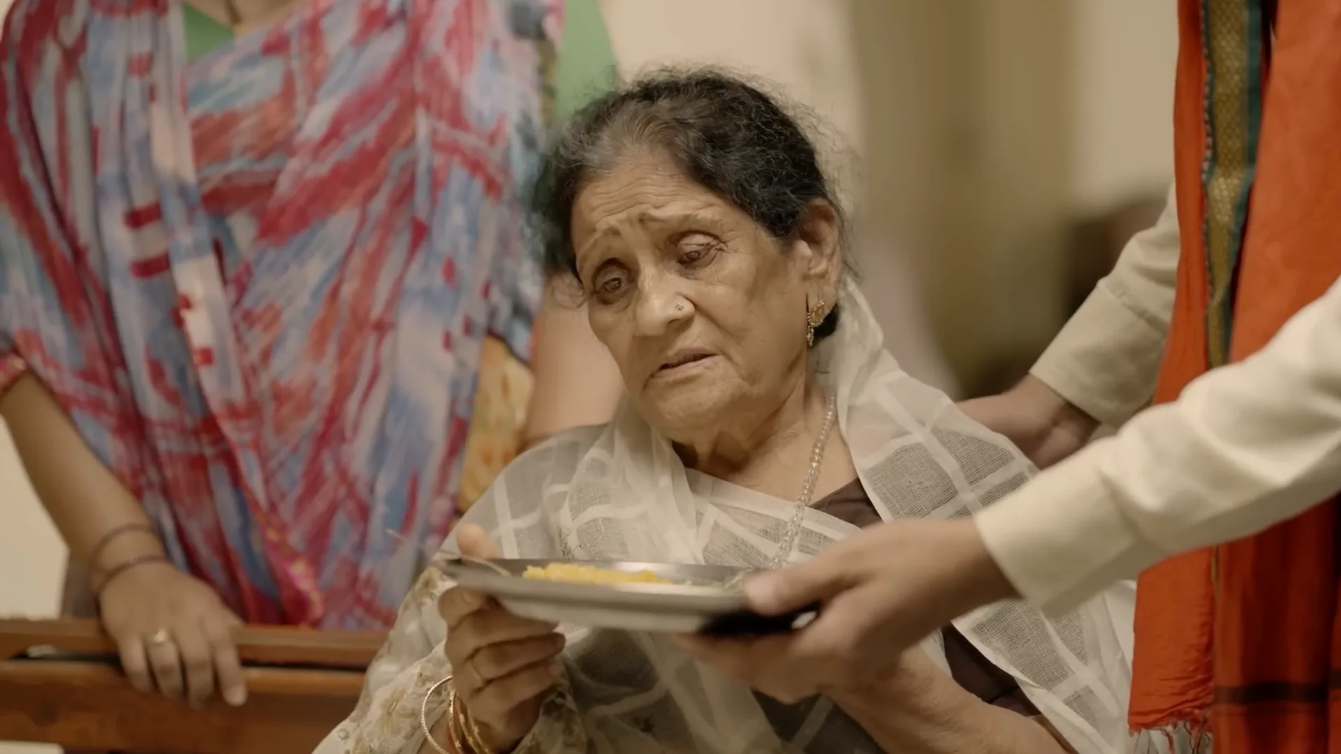 A mother is handed a plate by her son, from Jaise Maai Waise Betwa